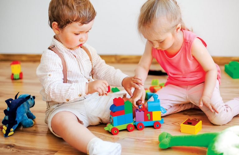 Two toddlers playing with a colourful toy train at Swan Academy
